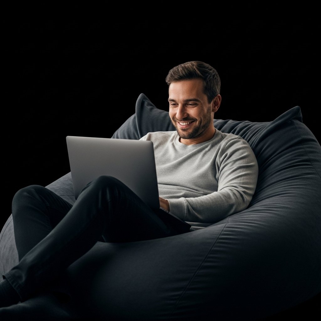 man smilling relaxed man on a sofa bean bag holding laptop